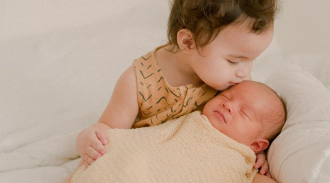 introduce child to new sibling baby kissing sister