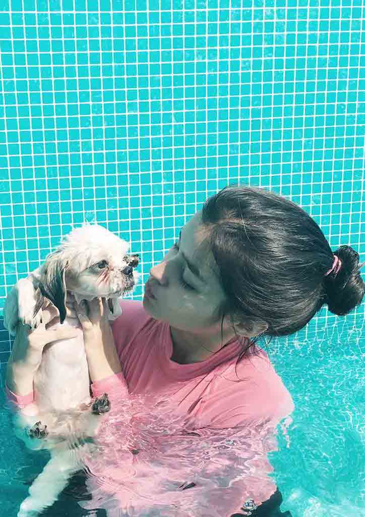 Girl in pink in swimming pool with her dog