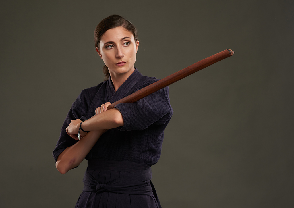 A female student-athlete holding an arnis stick.