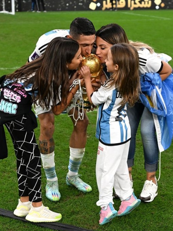 Ángel Di María, his wife, and their two daughters kiss the trophy