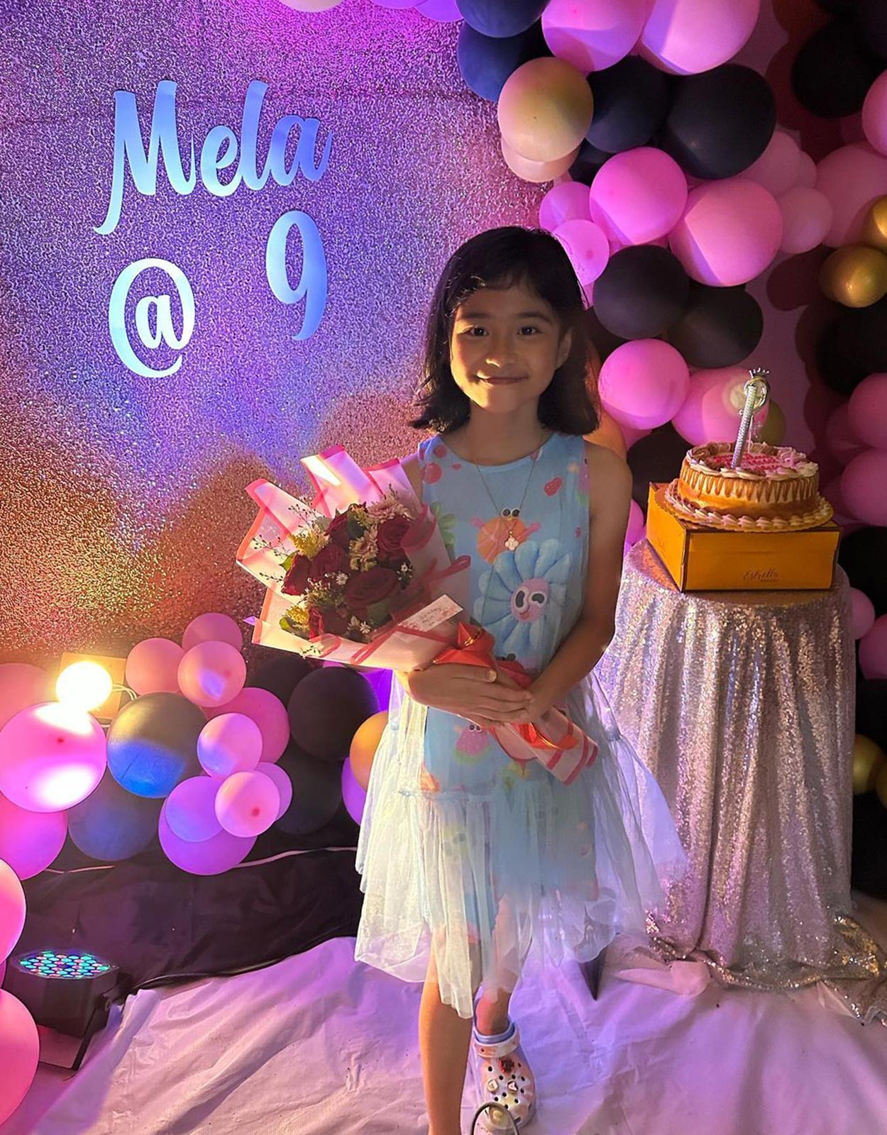 Mela Francisco holding flowers with a birthday cake in the background