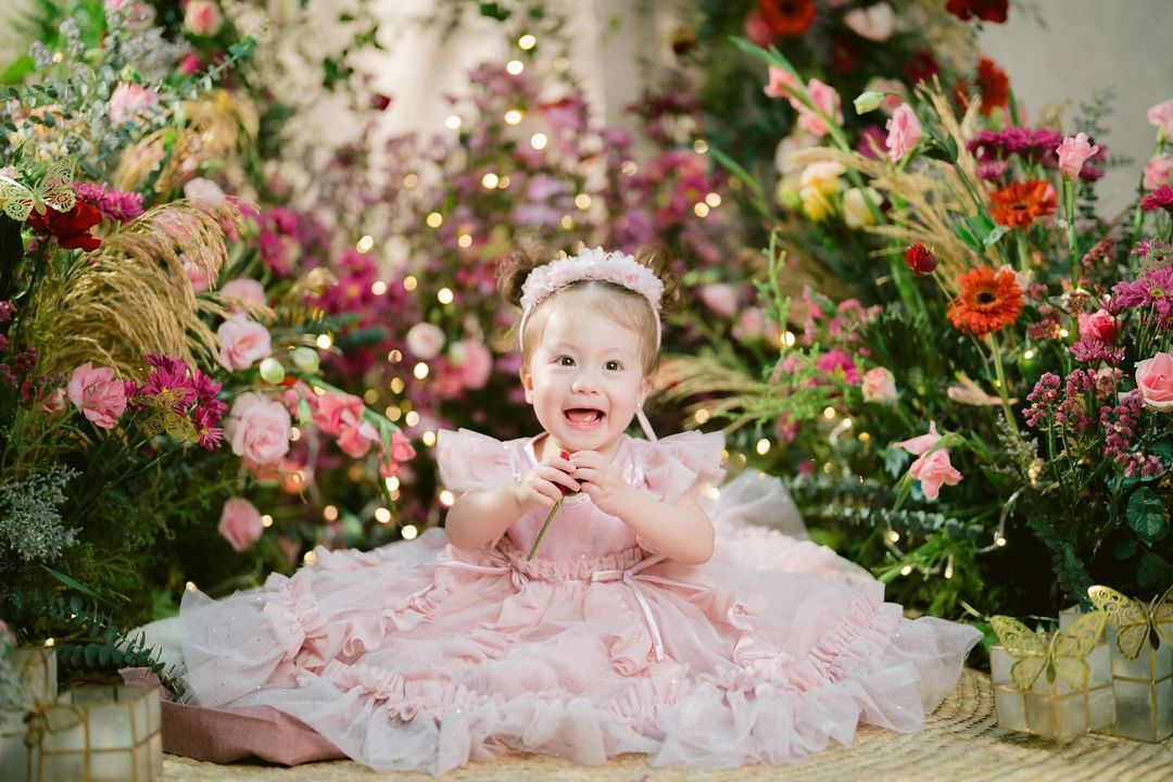 Jessy Mendiola and Luis Manzano's Daughter Isabella Rose sitting with a floral background